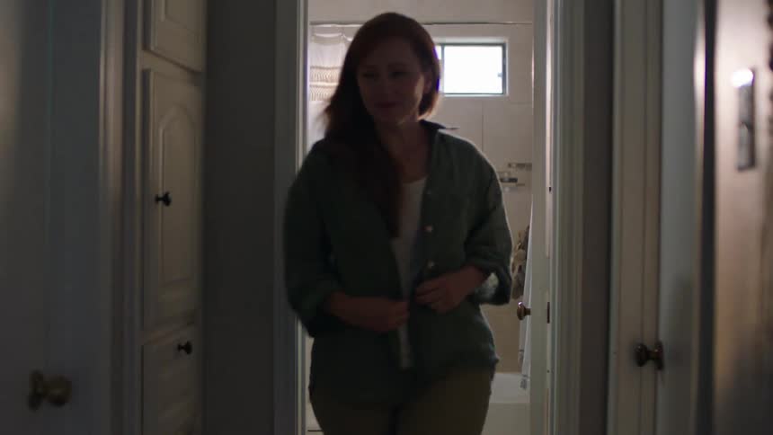 Woman with happy facial expression coming out of bathroom and walking in hallway at home