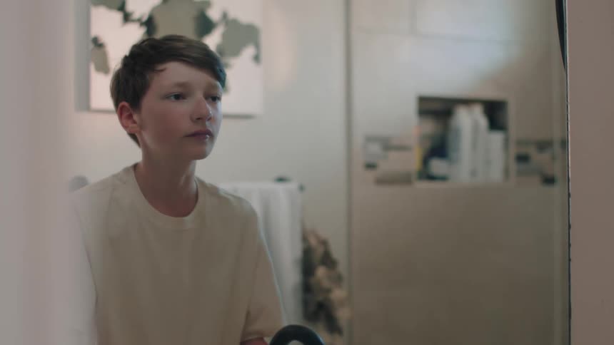 Boy washing his hands and face in front of the mirror in the bathroom