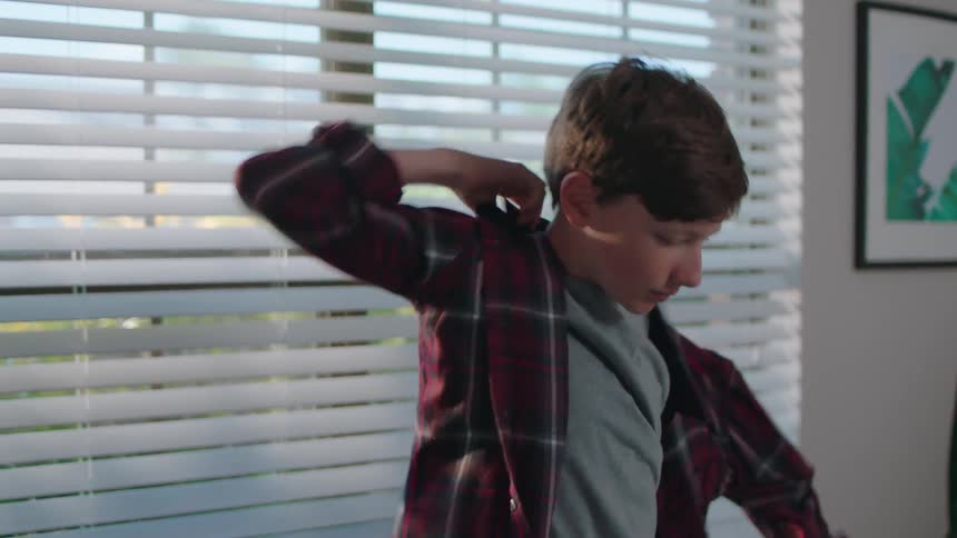 A boy is getting dressed at home