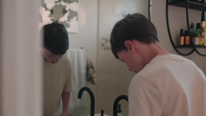 A teenage boy enter the bathroom to brush his teeth