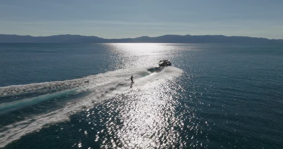 Aerial view of a person surfing with a rope attached to a moving yacht