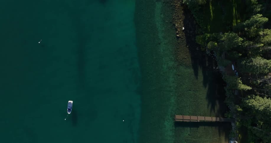 Aerial view of a boat in crystal clear waters near the coast with forest
