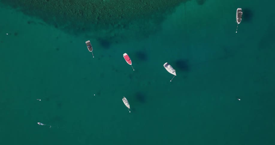 An aerial view of a body of water with scattered boats in various colors