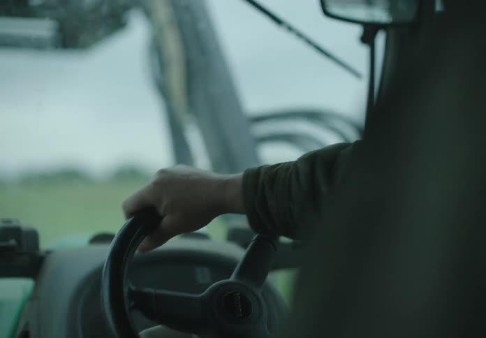 Persons hand on the steering wheel of a machine