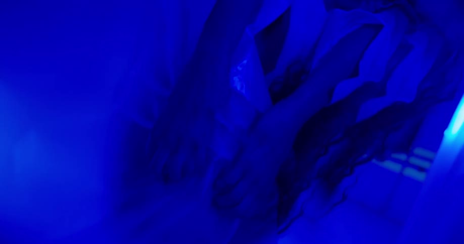 Reflection of a womans pair of hands moving in an environment with blue lights
