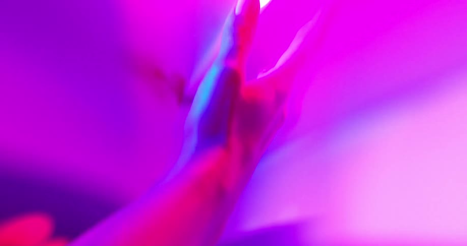 A couple of hands partially illuminated by streaks of flashing blue and magenta lights