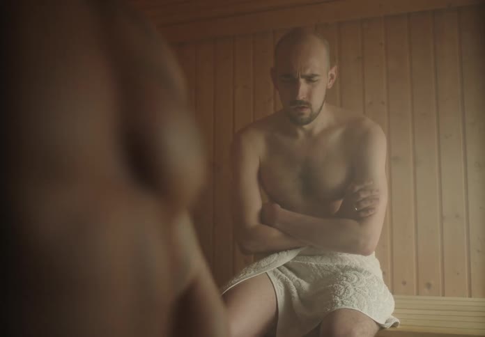 Man sitting in a sauna with a towel taking deep breaths