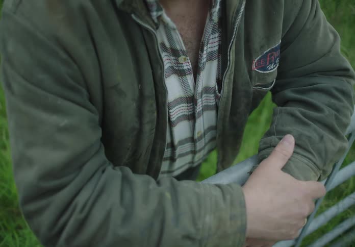 Man arms leaning on a railing in a pasture