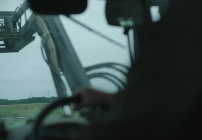 Person with hands on steering wheel driving agricultural machinery