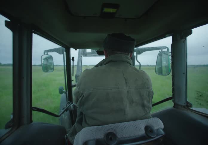 Man drives an agricultural vehicle across a field on an overcast day