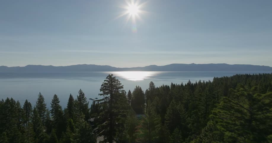 Boats float along a lake coast as the sun shines brightly overhead