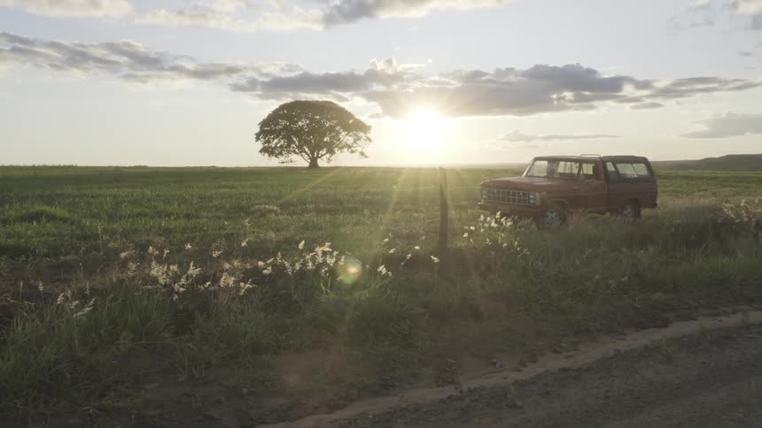 The sun rises over a truck parked in a grassland