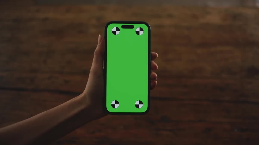 A person holding a cellphone out with a green screen on it
