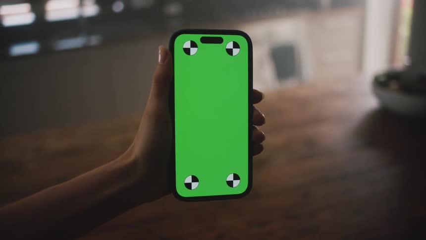 Cellphone being held out by a person with a wooden table behind it