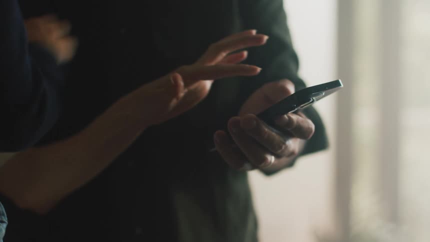 Father with black shirt uses smartphone next to mother and toddler son