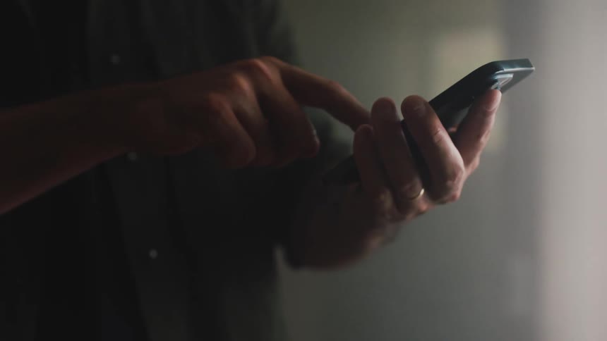 A man is holding a phone in his hand and scrolling with a finger on his other hand