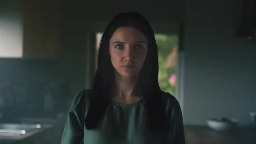 A woman is standing in the kitchen looking ahead