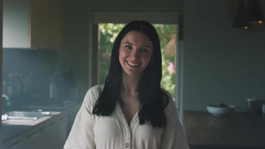 A woman standing in her kitchen posing for a photo while smiling