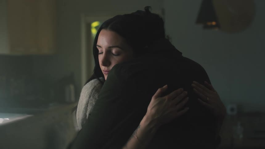 Mother in white shirt and father with black jacket cuddle and pick up toddler son