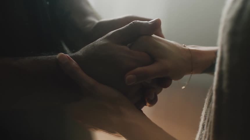 Close up of a couple holding hands comforting each other