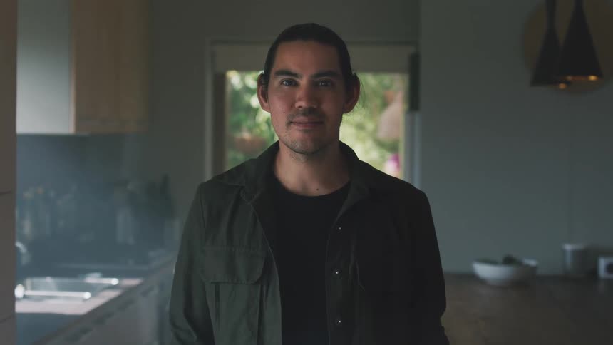 Man standing in his kitchen posed for a portrait with a neutral face