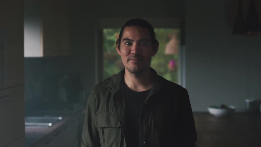Man smiles while posing in dimly lit kitchen