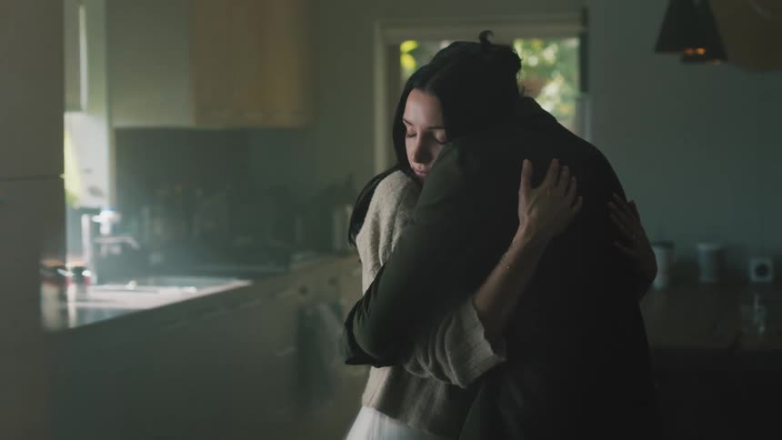 Couple hug each other in dimly lit kitchen