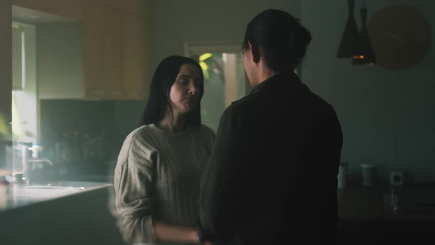 A woman and a man standing in a kitchen and talking with affection