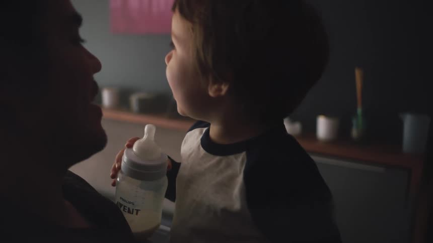 Father holds toddler son grasping the bottle