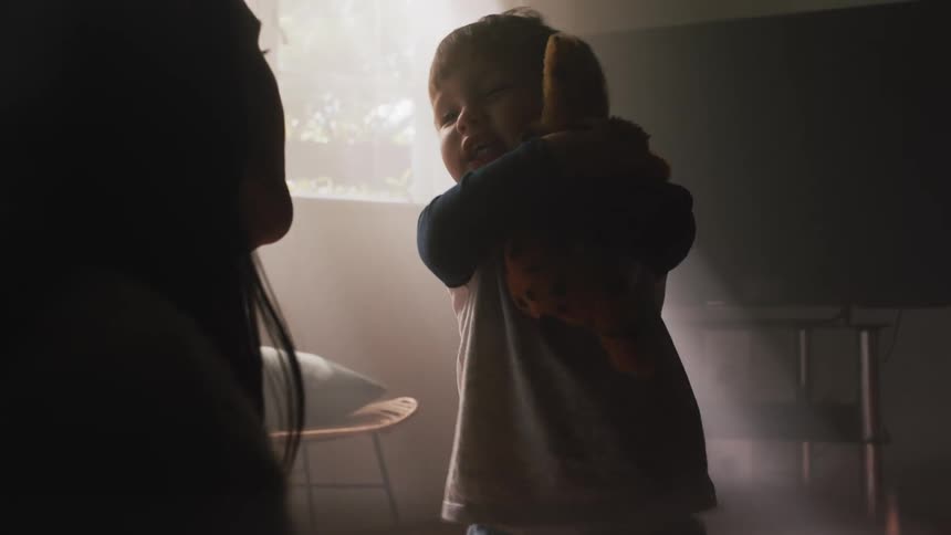 A boy hugs his toy tight while playing with his mom