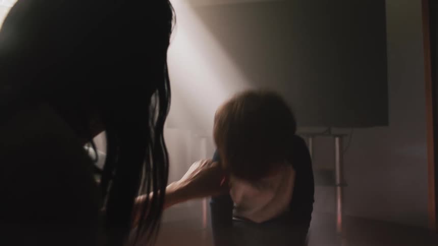Mother smiles and plays with toddler son guiding him in a dance in a dim room