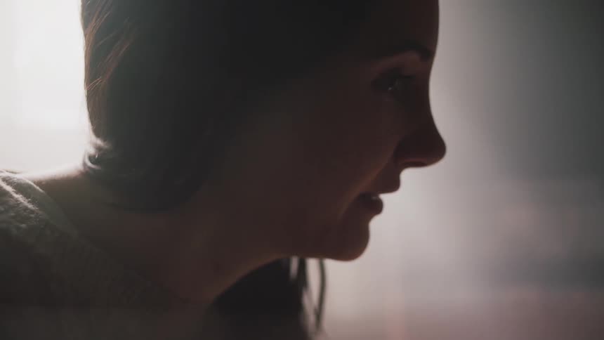 A woman is sitting indoors and talking to someone