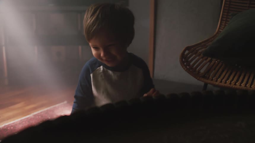 Mother and son play with stuffed toy in dimly lit room