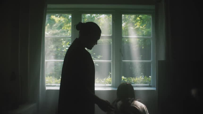 Mother father and baby son are silhouetted against the windows in building