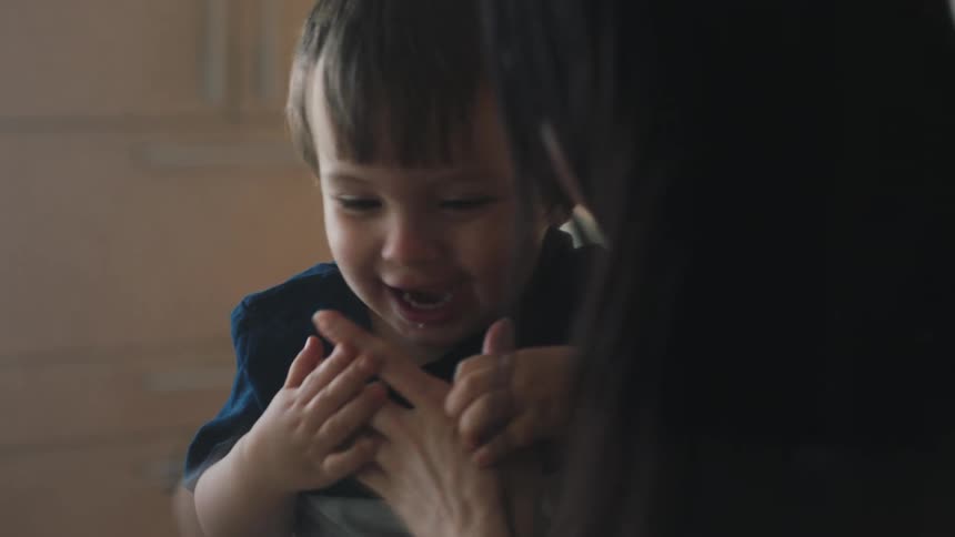 An adult woman plays with a little boy who pretends to bite her finger