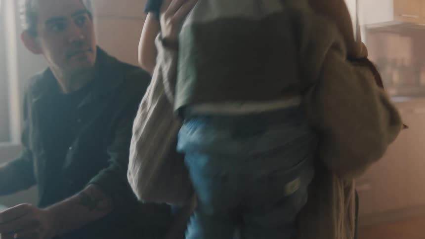A special family moment where a mother carries her son and puts him on her lap while the father look at them both
