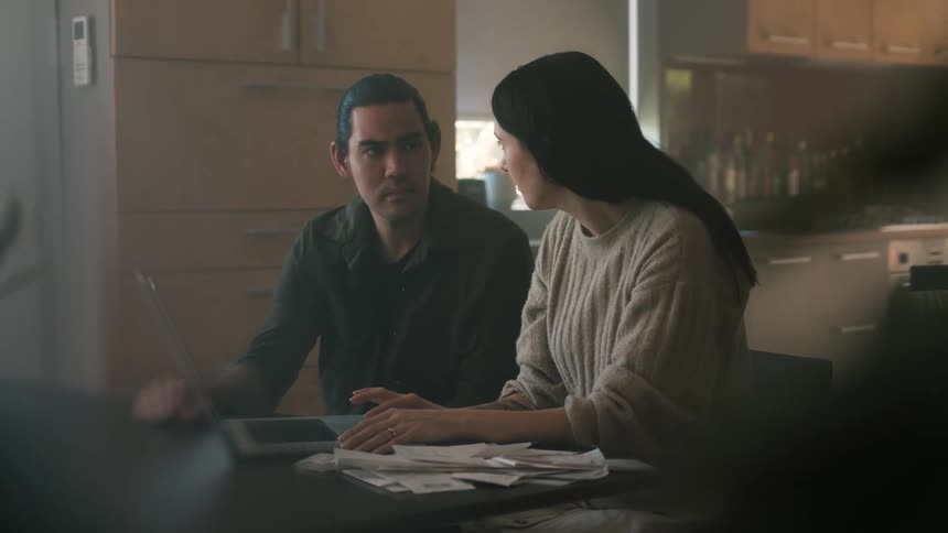 A man and woman chat while paying bills on a laptop