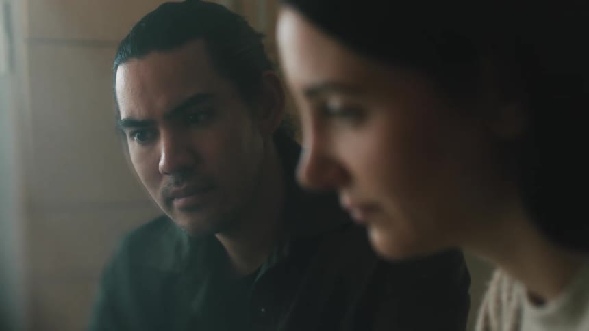 A man and a woman looking at something with sad expressions while the woman shakes her head the man looks at her with a shocked expression suggesting that they have witnessed or heard something disturbing