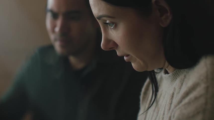A woman shakes her head while looking at something with another person