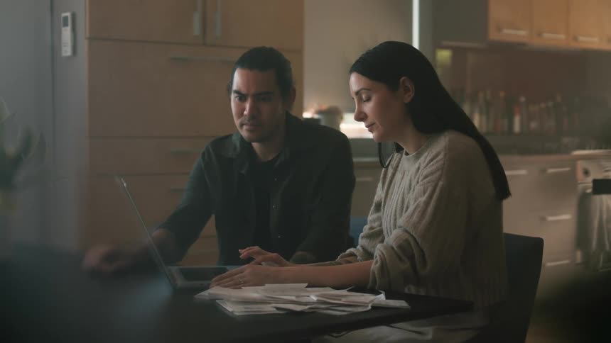 A couple pay bills together on their laptop