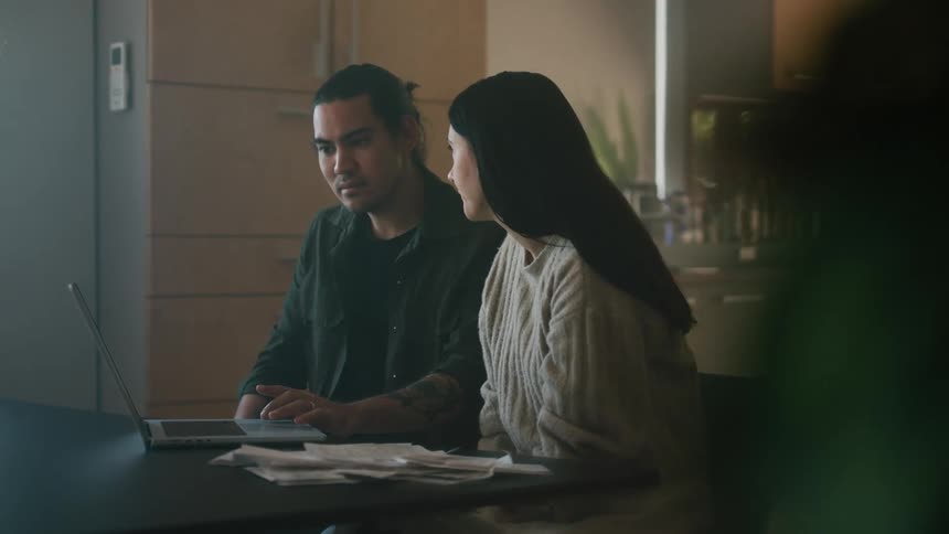A man and woman pays bills on their laptop