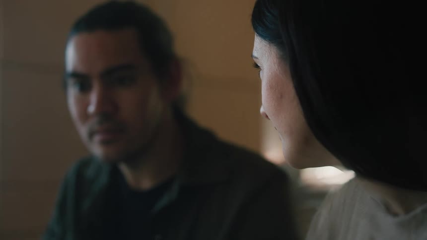 A man and woman sit near each other while conversing and the woman smiles