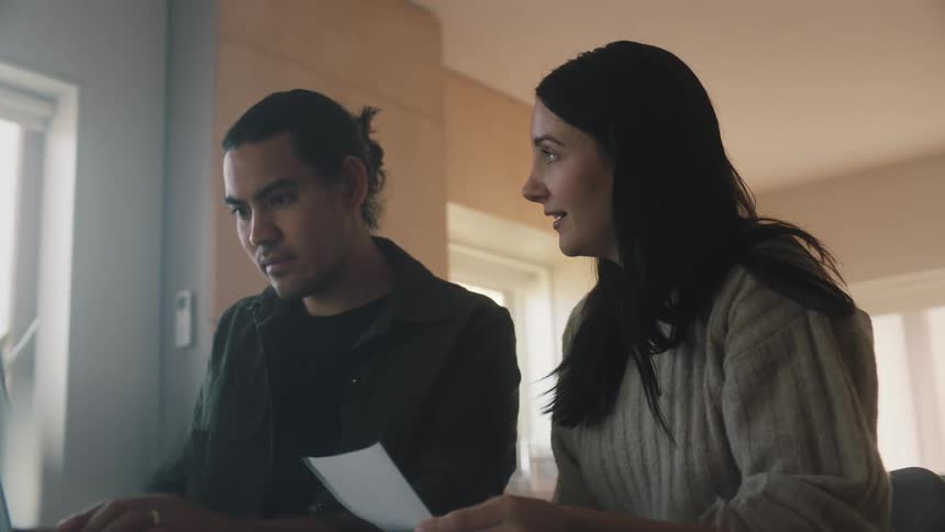 Man and woman work together on receipts with a laptop