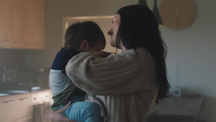 A mother gives her son some kisses