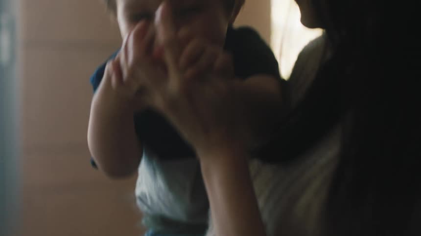 A mother holds her son who is laughing