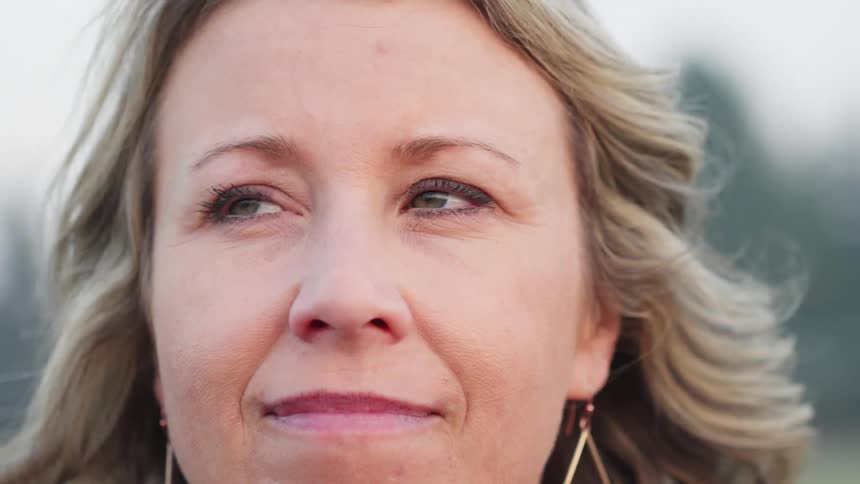 A white woman stands in nature and looks around