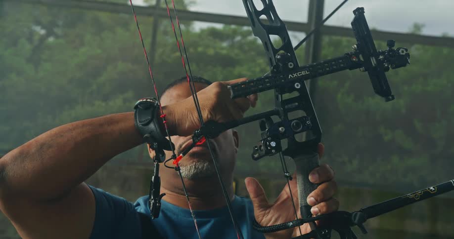 Older man nocks an arrow against the bowstring of a modern bow