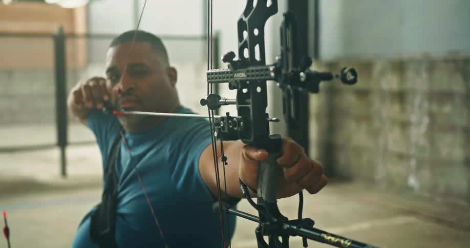 A man using a professional string bow to aim an arrow then letting the arrow fly