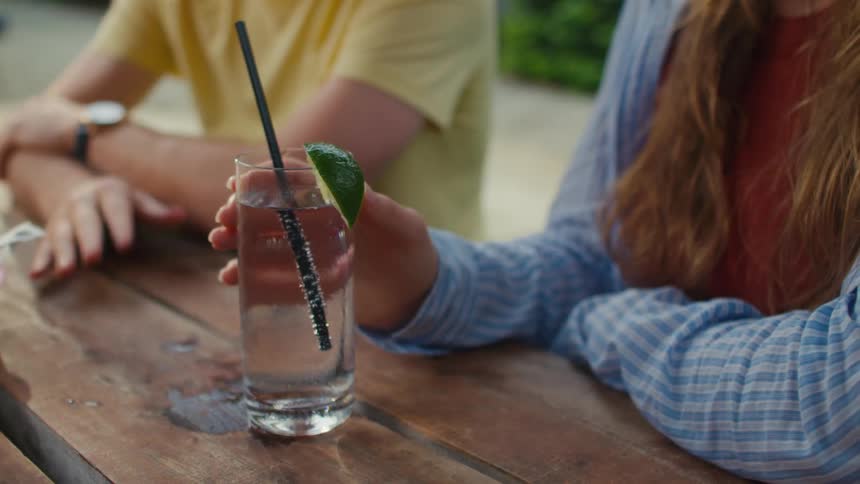 A woman holds a glass at the table with friends