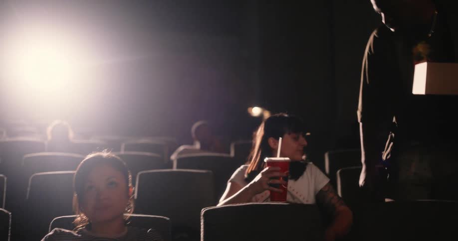 People sitting in a movie theater eating popcorn